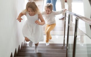 Two children running up the stairs of a home