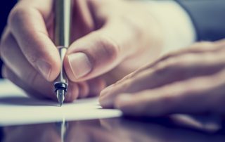 Close up of a hand holding a pen to paper