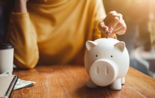 A woman depositing a coin into a piggy bank.
