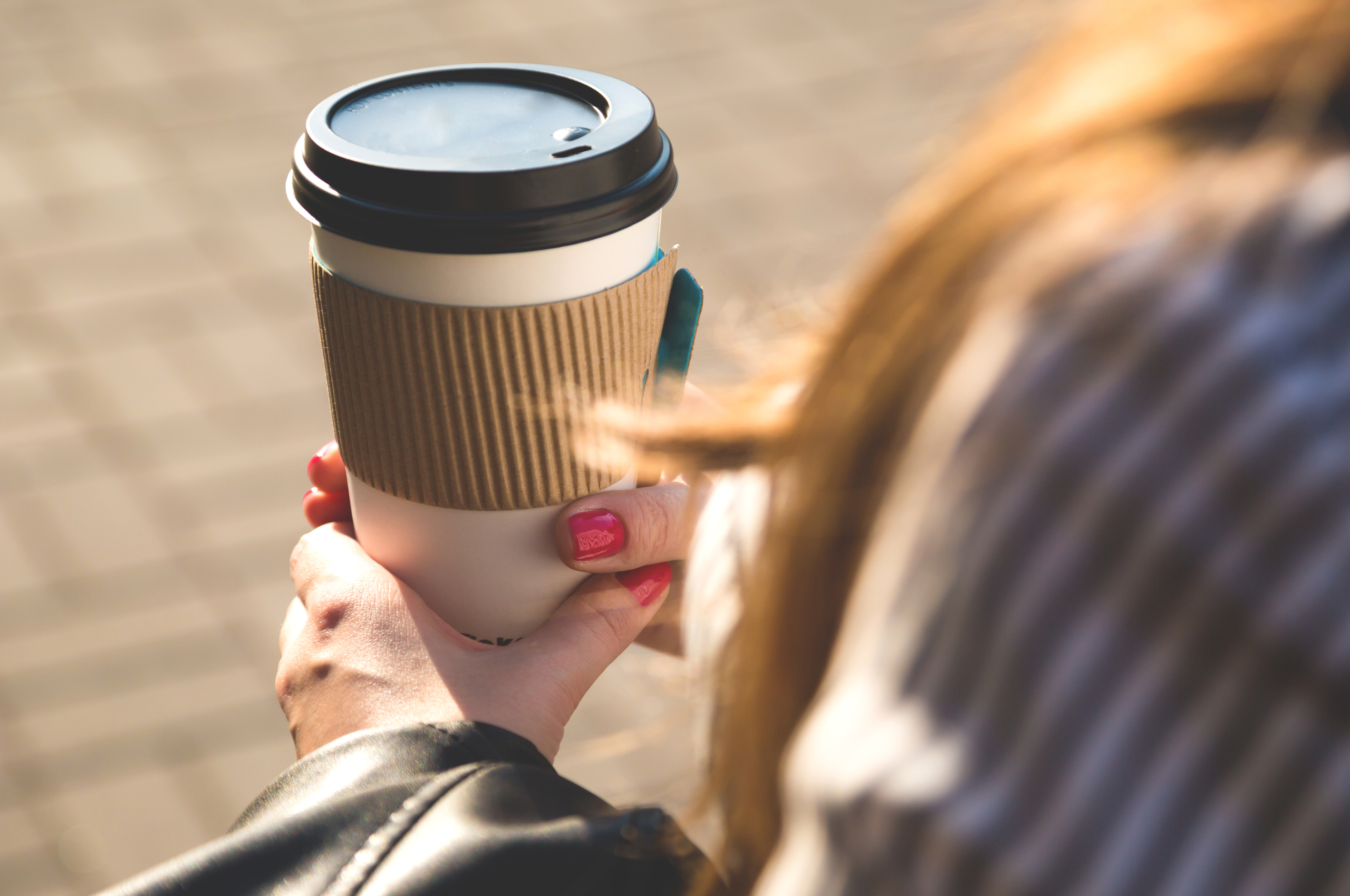 A woman holding a takeaway cup of coffee.