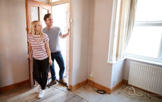 A young couple walking through the front door of an empty home.