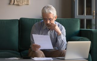 An older man reviewing some paperwork at home.
