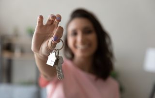 A woman holding out house keys.