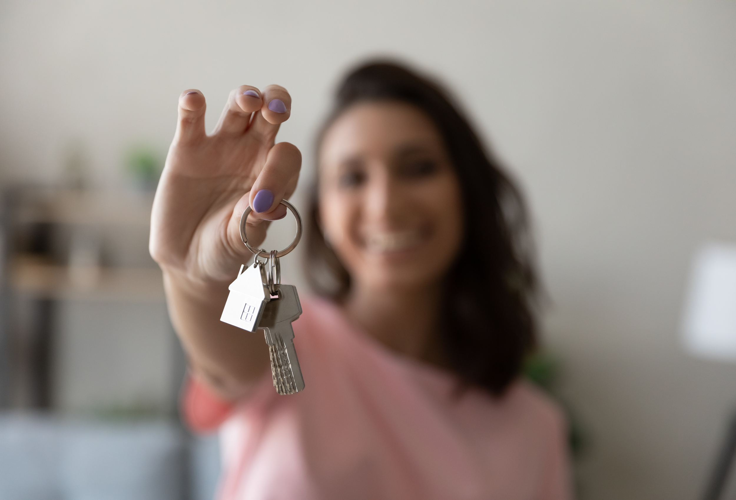 A woman holding out house keys.
