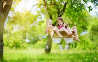 Two girls playing on a swing.