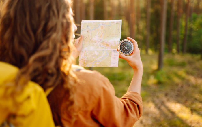 A young woman hiking and using a compass.