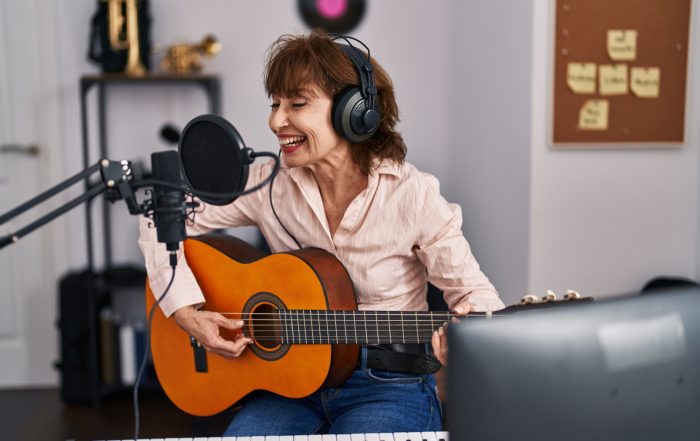 A woman playing a guitar in a music studio.