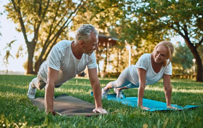 A couple doing yoga in a park.