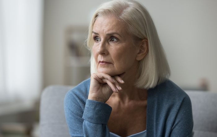 An older woman looks pensively off to one side.