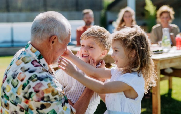 A grandfather playing with his grandchildren outdoors.