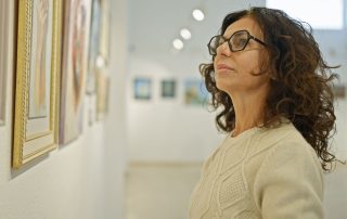 A woman looking at a painting in an art gallery.