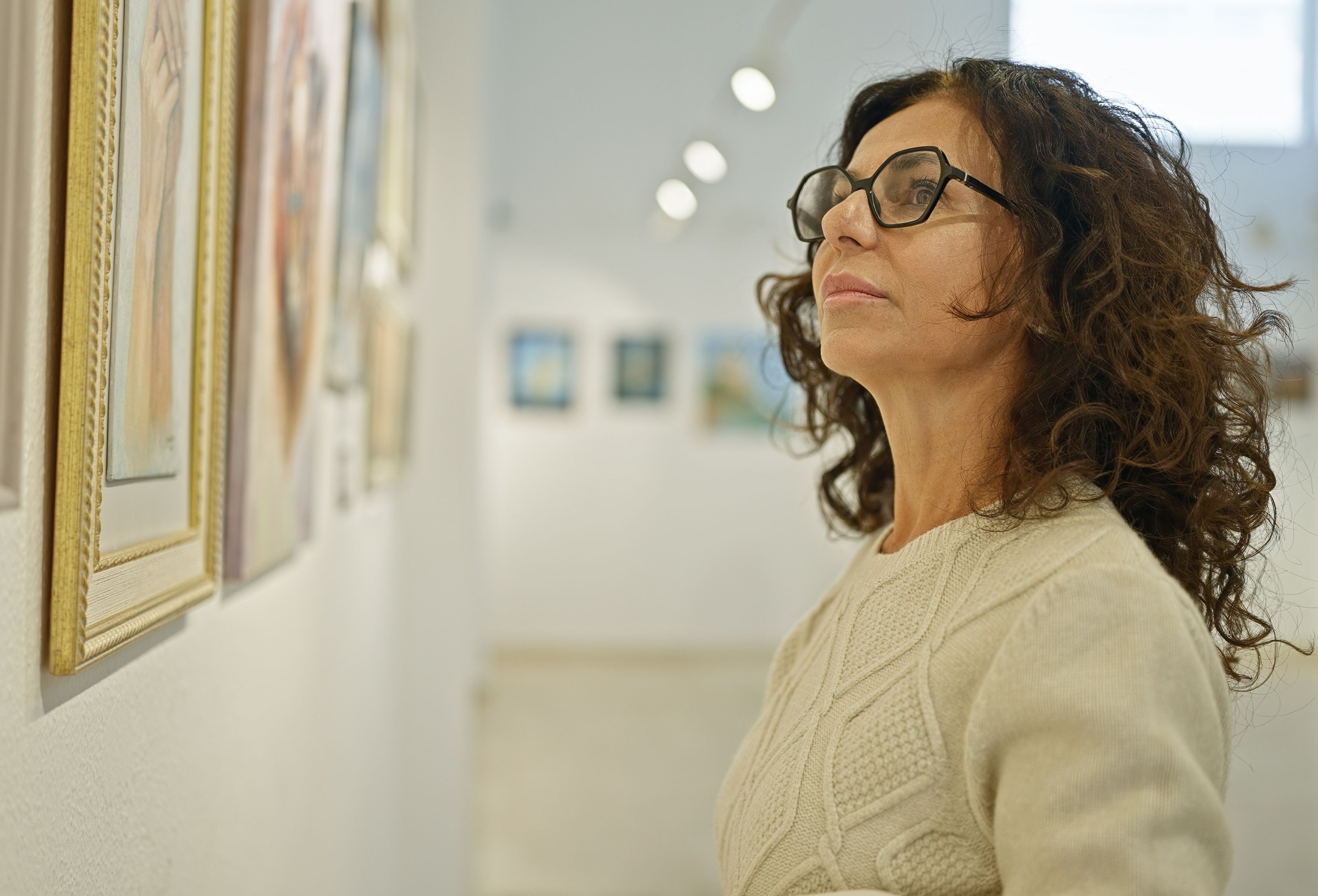 A woman looking at a painting in an art gallery.