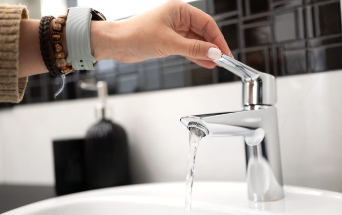 A person testing a tap in a bathroom.